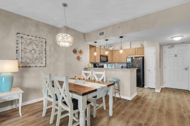 dining area with light wood-type flooring, baseboards, a chandelier, and visible vents