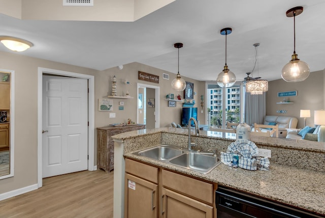 kitchen featuring hanging light fixtures, black dishwasher, a sink, open floor plan, and light wood-type flooring
