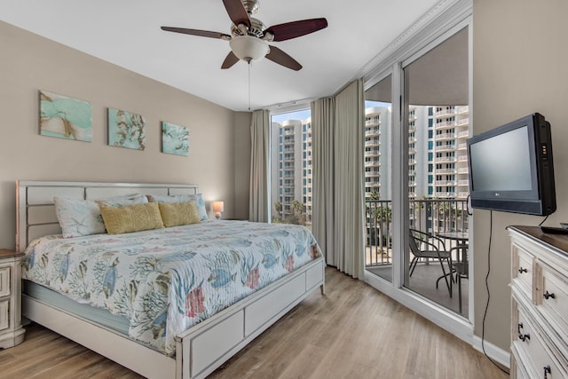 bedroom with floor to ceiling windows, light wood finished floors, ceiling fan, and access to exterior