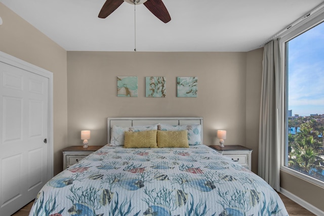 bedroom featuring multiple windows, wood finished floors, baseboards, and ceiling fan
