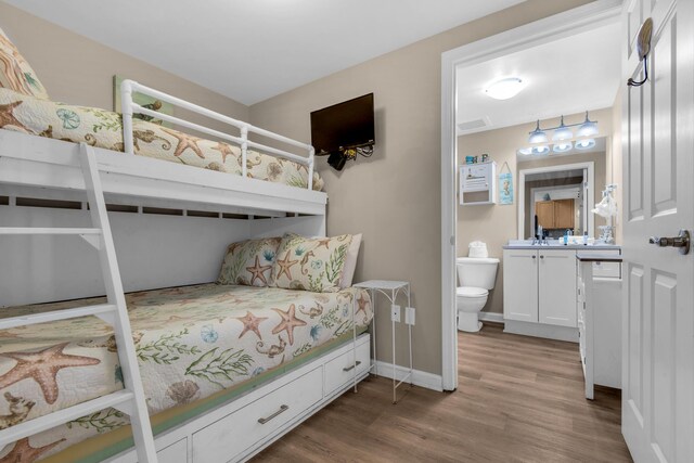 bedroom with baseboards, visible vents, and wood finished floors