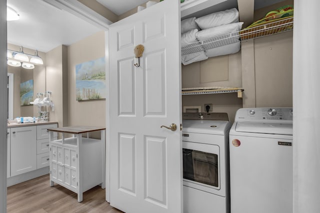 laundry area with light wood finished floors, washing machine and clothes dryer, and laundry area