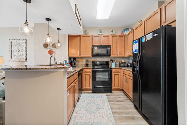 4203 Indian Bayou Trl Unit 1503, Destin, FL 32541 - kitchen featuring black appliances, a peninsula, light wood finished floors, light stone counters, and hanging light fixtures