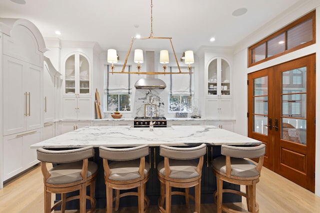 50 Camellia St, Santa Rosa Beach, FL 32459 - kitchen with french doors, an island with sink, light wood-style flooring, glass insert cabinets, and recessed lighting