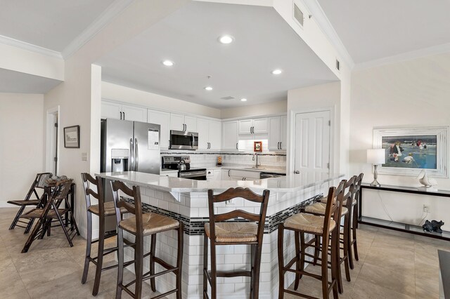 kitchen featuring appliances with stainless steel finishes, a sink, crown molding, white cabinets, and decorative backsplash