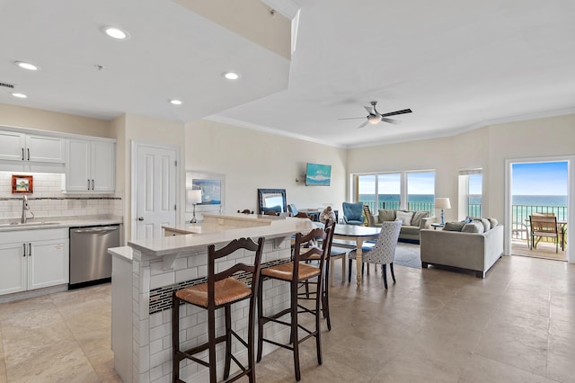 kitchen with stainless steel dishwasher, a sink, crown molding, ceiling fan, and decorative backsplash