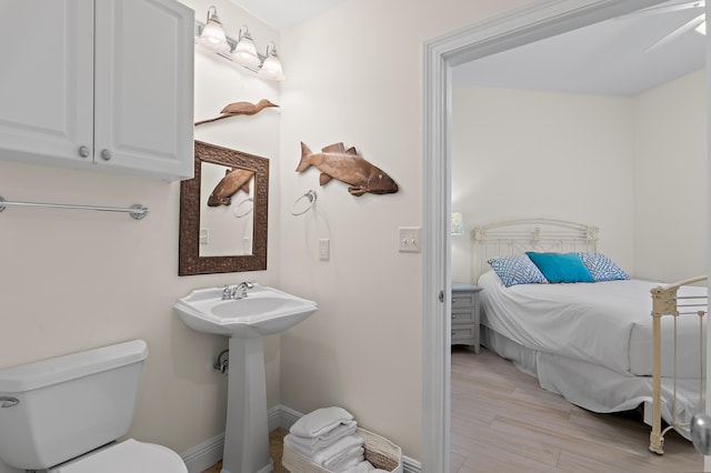 bathroom with wood finished floors, toilet, connected bathroom, and baseboards