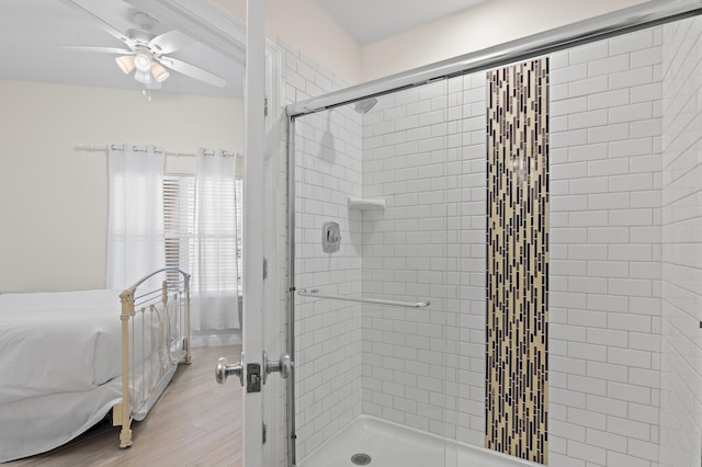 ensuite bathroom featuring a shower stall, a ceiling fan, and wood finished floors