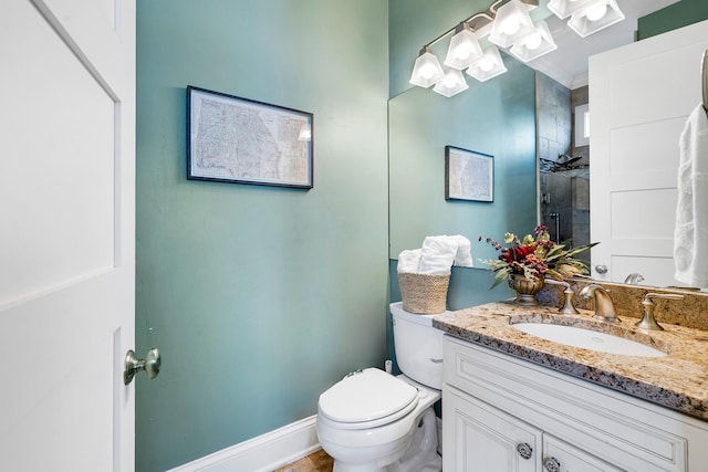 bathroom with toilet, baseboards, a tile shower, and vanity