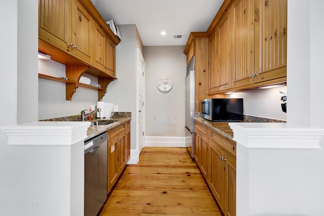 kitchen featuring open shelves, a sink, baseboards, light wood-style floors, and stainless steel appliances