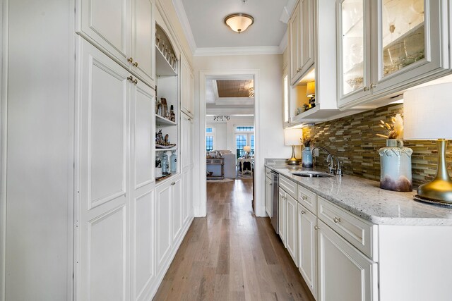 interior space with crown molding, tasteful backsplash, stainless steel dishwasher, wood finished floors, and a sink