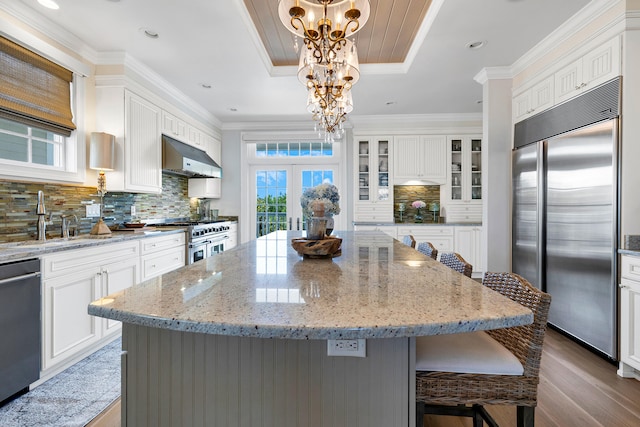 kitchen featuring an inviting chandelier, under cabinet range hood, french doors, a sink, and premium appliances