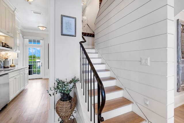 stairs featuring crown molding, wood finished floors, and visible vents