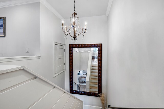 foyer entrance with crown molding and a chandelier