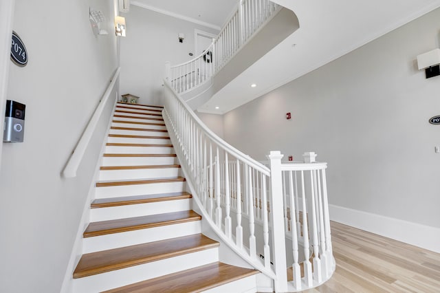 stairs with crown molding, recessed lighting, baseboards, and wood finished floors