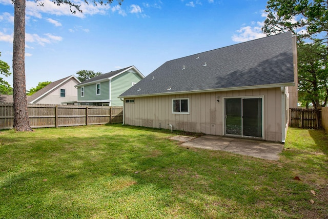 rear view of property featuring roof with shingles, a patio, a lawn, and a fenced backyard