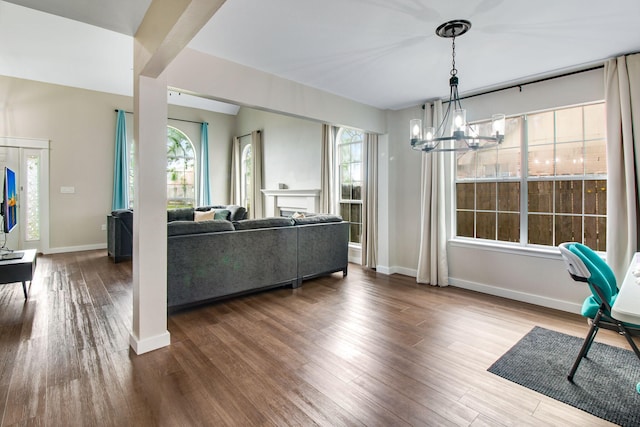 living room with baseboards, a wealth of natural light, wood finished floors, and a chandelier
