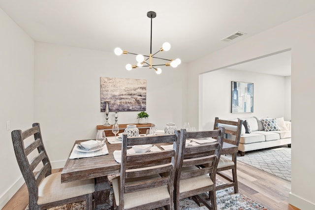 dining room with visible vents, light wood-style floors, baseboards, and a notable chandelier
