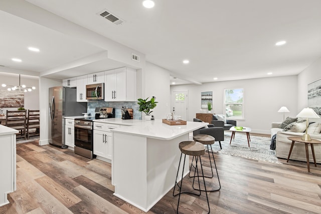 kitchen featuring visible vents, decorative backsplash, open floor plan, a breakfast bar area, and stainless steel appliances