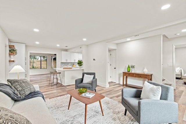living room with baseboards, recessed lighting, and light wood-style flooring