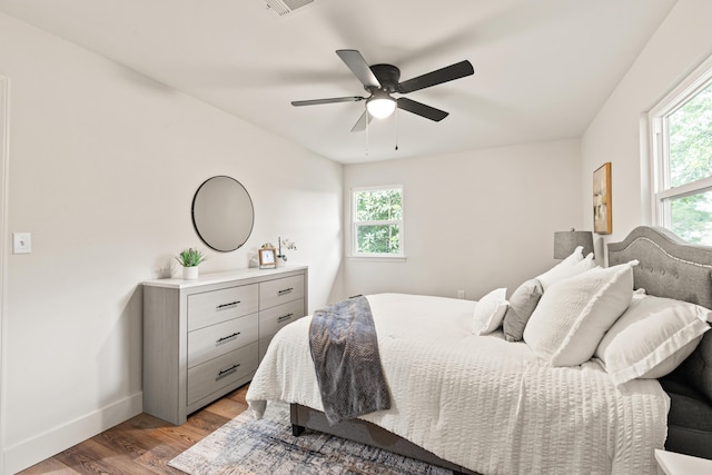 bedroom featuring baseboards, multiple windows, a ceiling fan, and light wood-type flooring