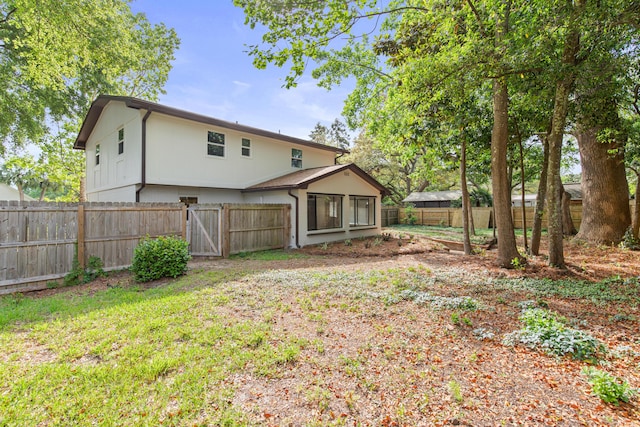 back of house with a fenced backyard and a gate