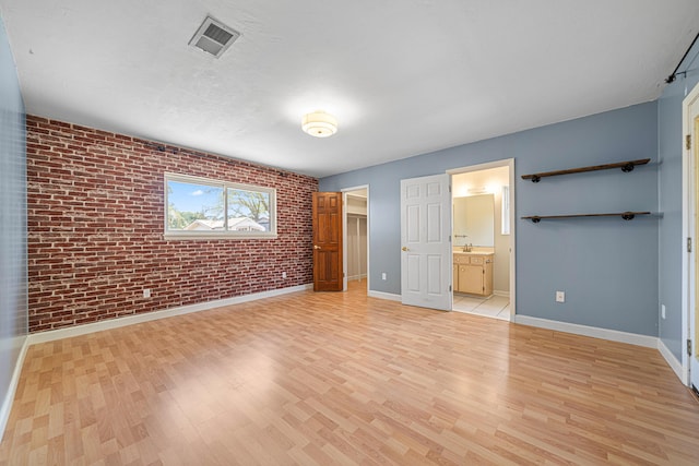 1501 Royal Palm Dr, Niceville, FL 32578 - unfurnished bedroom featuring brick wall, light wood-style flooring, baseboards, a spacious closet, and a closet