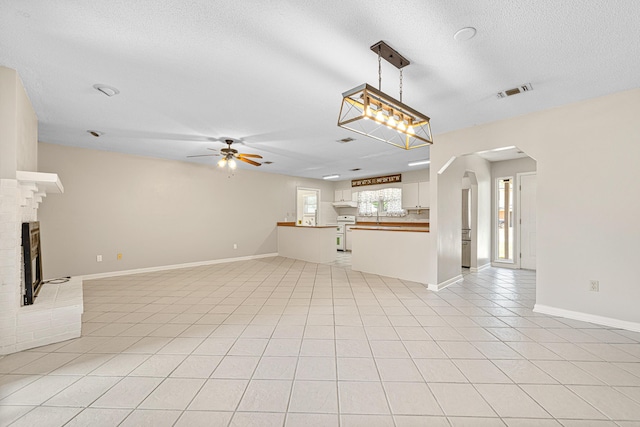 1501 Royal Palm Dr, Niceville, FL 32578 - unfurnished living room featuring a ceiling fan, a brick fireplace, arched walkways, light tile patterned floors, and a textured ceiling