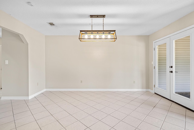 1501 Royal Palm Dr, Niceville, FL 32578 - spare room featuring french doors, arched walkways, light tile patterned floors, baseboards, and a textured ceiling