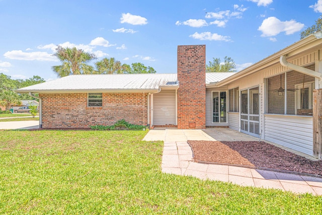 1501 Royal Palm Dr, Niceville, FL 32578 - view of front of house featuring a chimney, a front yard, brick siding, metal roof, and a patio