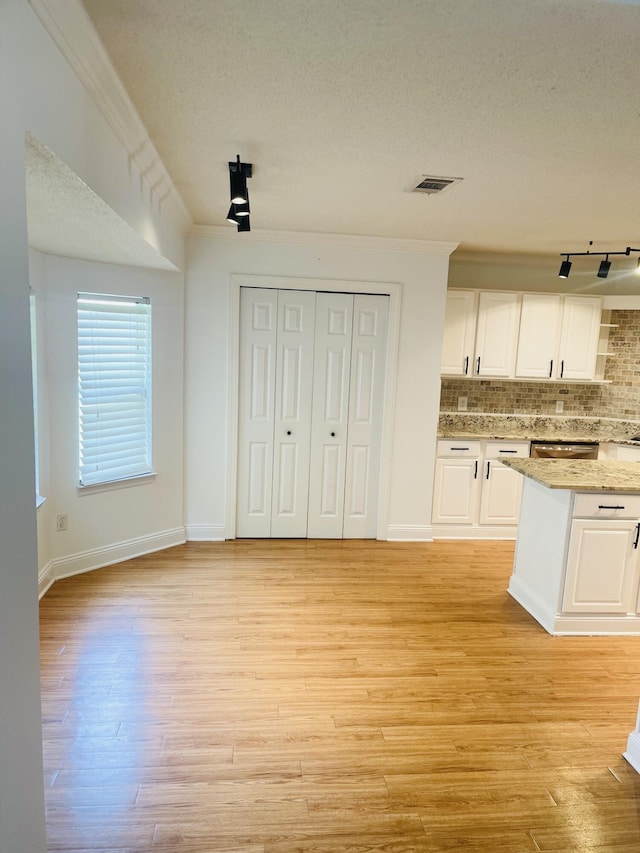 437 Hatchee Dr, Crestview, FL 32536 - kitchen with white cabinetry, decorative backsplash, light wood-style floors, a textured ceiling, and light stone countertops