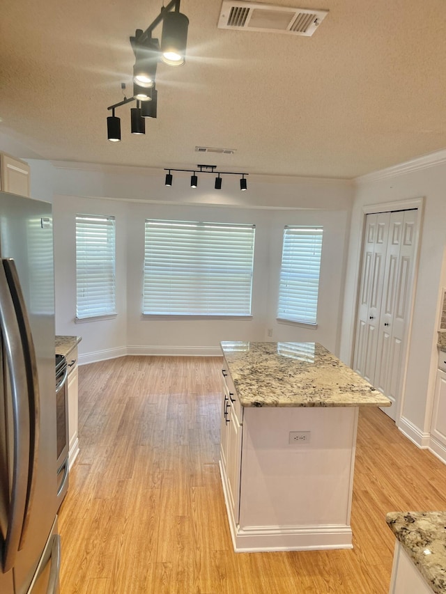 437 Hatchee Dr, Crestview, FL 32536 - kitchen featuring freestanding refrigerator, rail lighting, light wood-style flooring, white cabinetry, and a textured ceiling