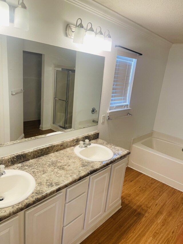 437 Hatchee Dr, Crestview, FL 32536 - full bathroom with double vanity, a bath, wood finished floors, a shower stall, and a textured ceiling