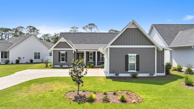 view of front of home with roof with shingles, board and batten siding, and a front lawn