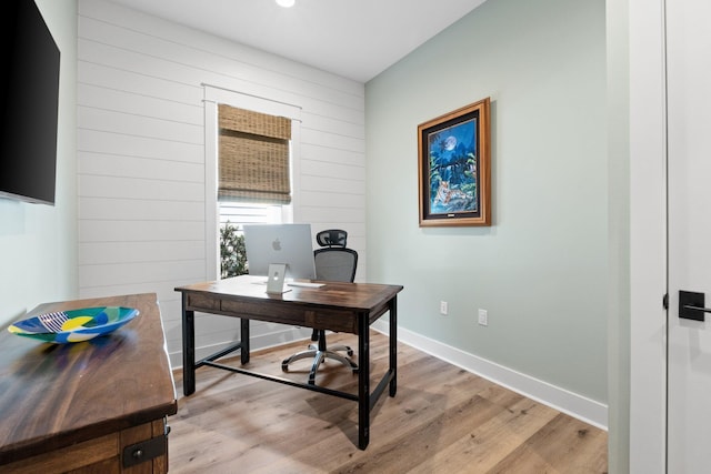 office featuring baseboards, wood walls, and light wood-type flooring