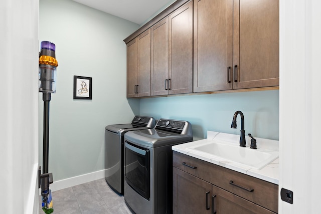 laundry area with baseboards, a sink, cabinet space, and washing machine and clothes dryer