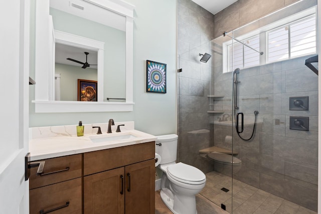 full bath featuring ceiling fan, vanity, toilet, visible vents, and a stall shower