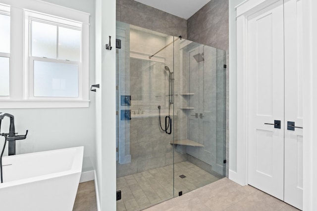 full bathroom with tile patterned flooring, a soaking tub, and a shower stall