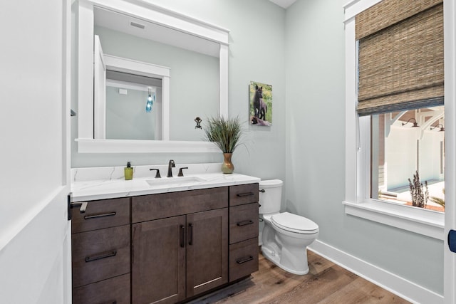 bathroom featuring vanity, toilet, baseboards, wood finished floors, and visible vents