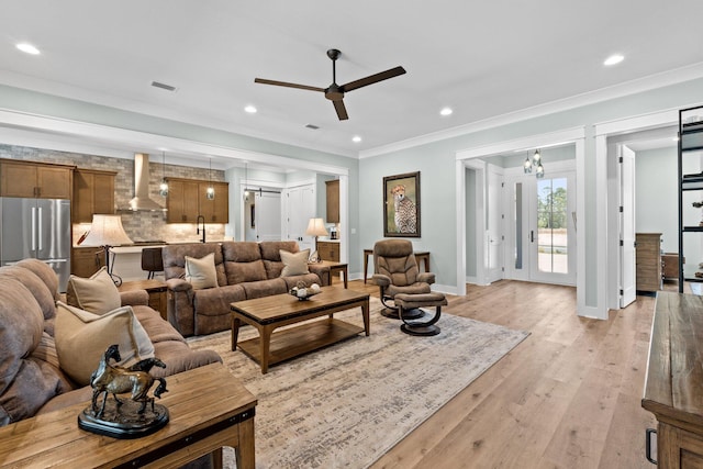 living area featuring recessed lighting, baseboards, ornamental molding, and ceiling fan with notable chandelier
