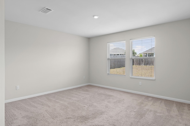 carpeted empty room featuring baseboards and visible vents
