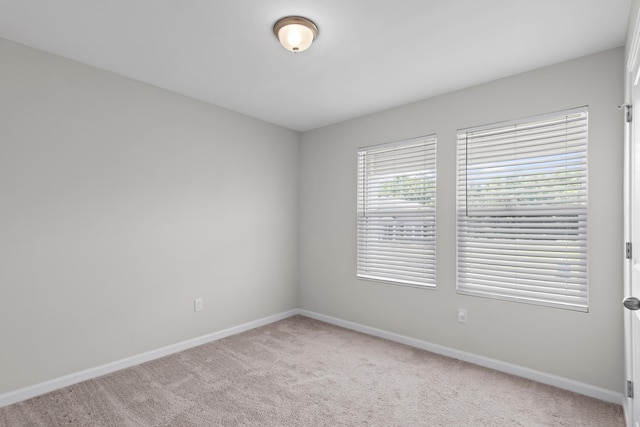 spare room featuring carpet flooring and baseboards