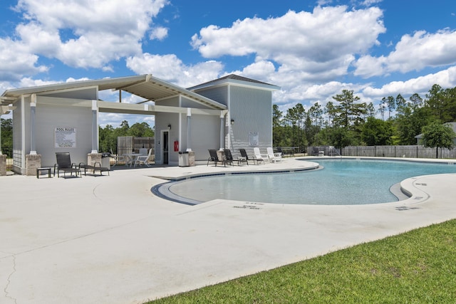community pool with a patio area and fence