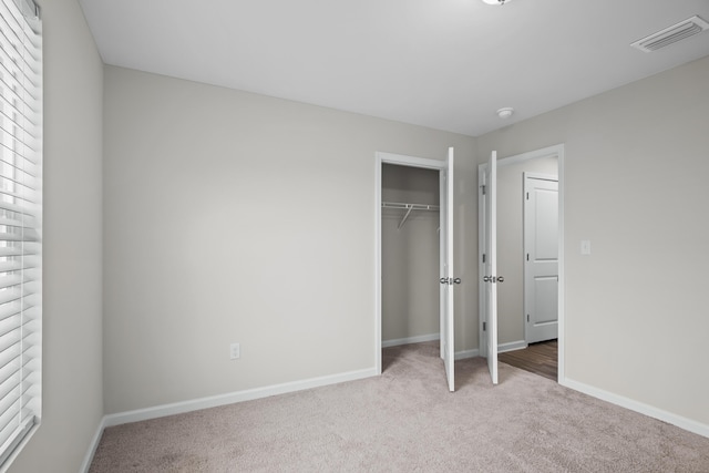 unfurnished bedroom featuring carpet flooring, baseboards, a closet, and visible vents