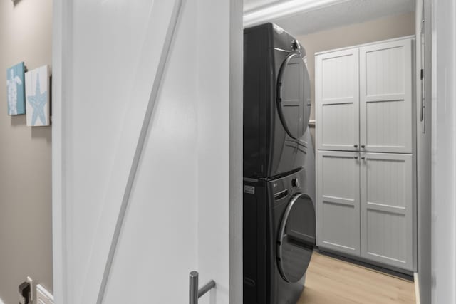 399 Linkside Dr, Miramar Beach, FL 32550 - clothes washing area featuring stacked washer / drying machine, cabinet space, and light wood finished floors