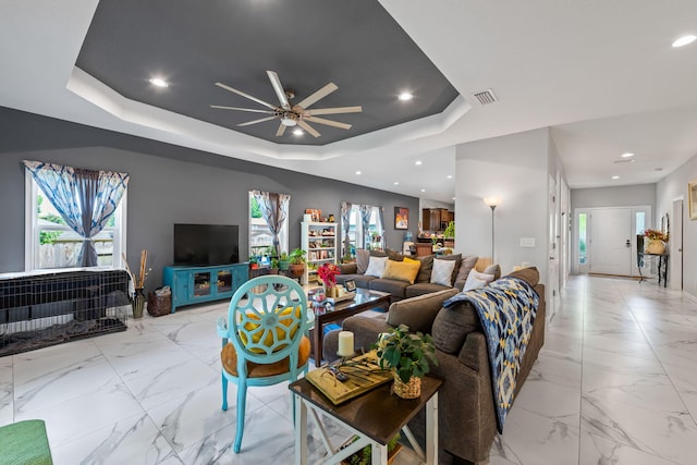 living area featuring a tray ceiling, marble finish floors, ceiling fan, healthy amount of natural light, and recessed lighting