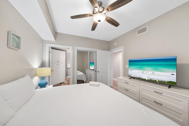 bedroom with visible vents, a closet, wood finished floors, baseboards, and ceiling fan