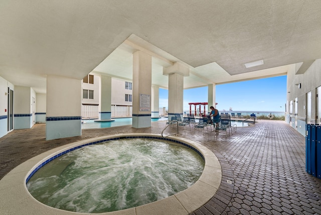 view of swimming pool featuring a water view and an indoor in ground hot tub