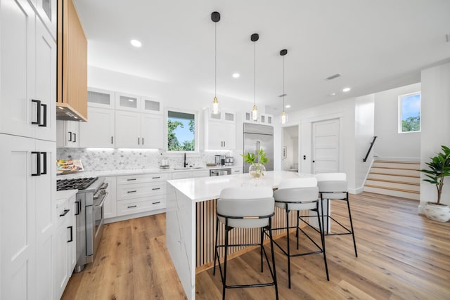 2456 Belmar Ct, Panama City Beach, FL 32408 - kitchen featuring high end appliances, a kitchen island, a breakfast bar area, a sink, and backsplash