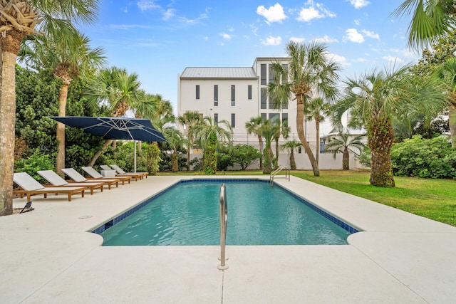 pool with a patio and a lawn